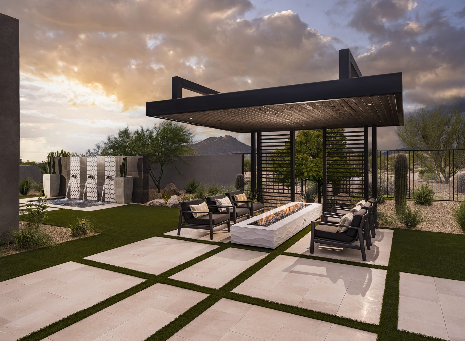 Travertine pavers with turf joints beneath a steel ramada at dusk