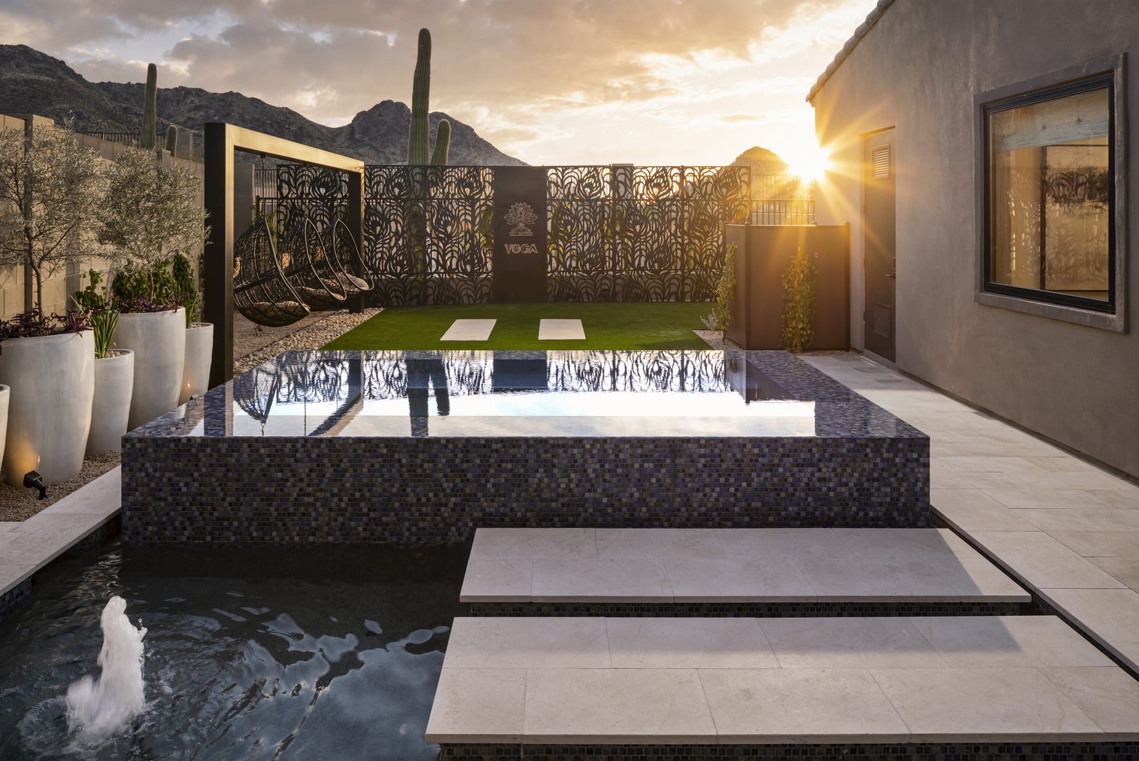 Custom pool with architectural water feature in a desert-modern backyard at dusk