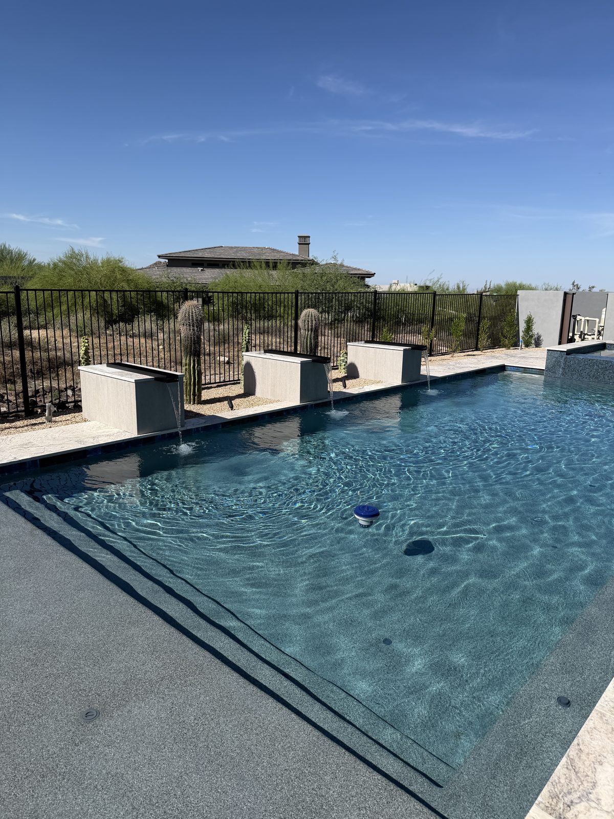 Pool with three linear scupper water features and travertine deck