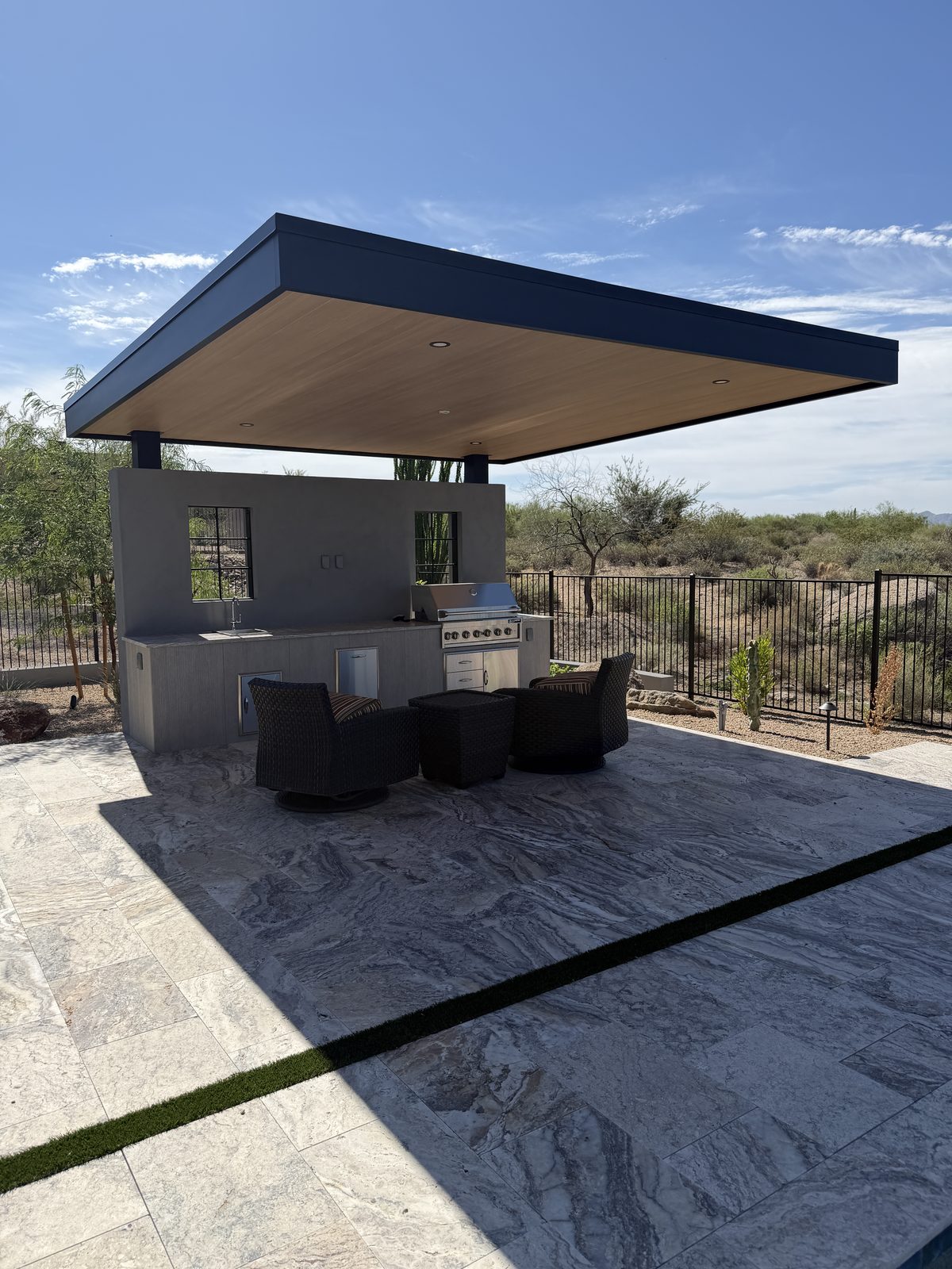 Covered outdoor kitchen with built-in grill and travertine patio